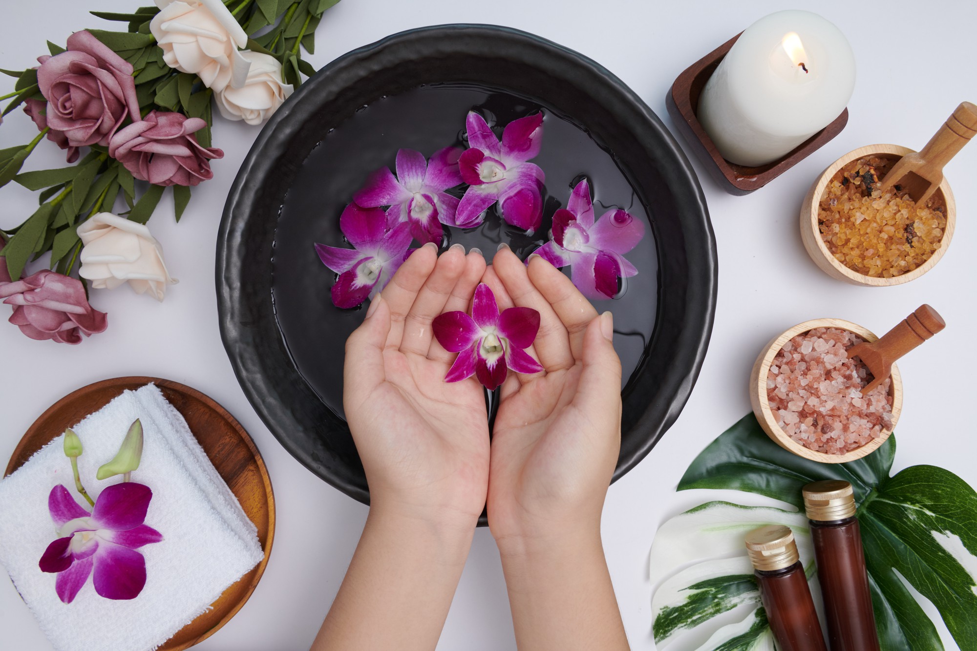 woman soaking her hands bowl water flowers spa treatment product female feet hand spa massage pebble perfumed flowers water candles relaxation flat lay top view
