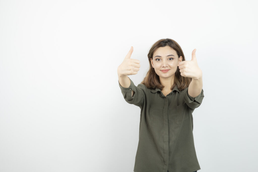 Beautiful young woman in casual outfit standing and giving thumbs up